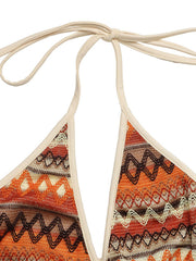 Geometric pattern halter jumpsuit with beige trim and tie neck.