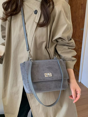 Sleek gray suede crossbody bag with flap closure and silver hardware.