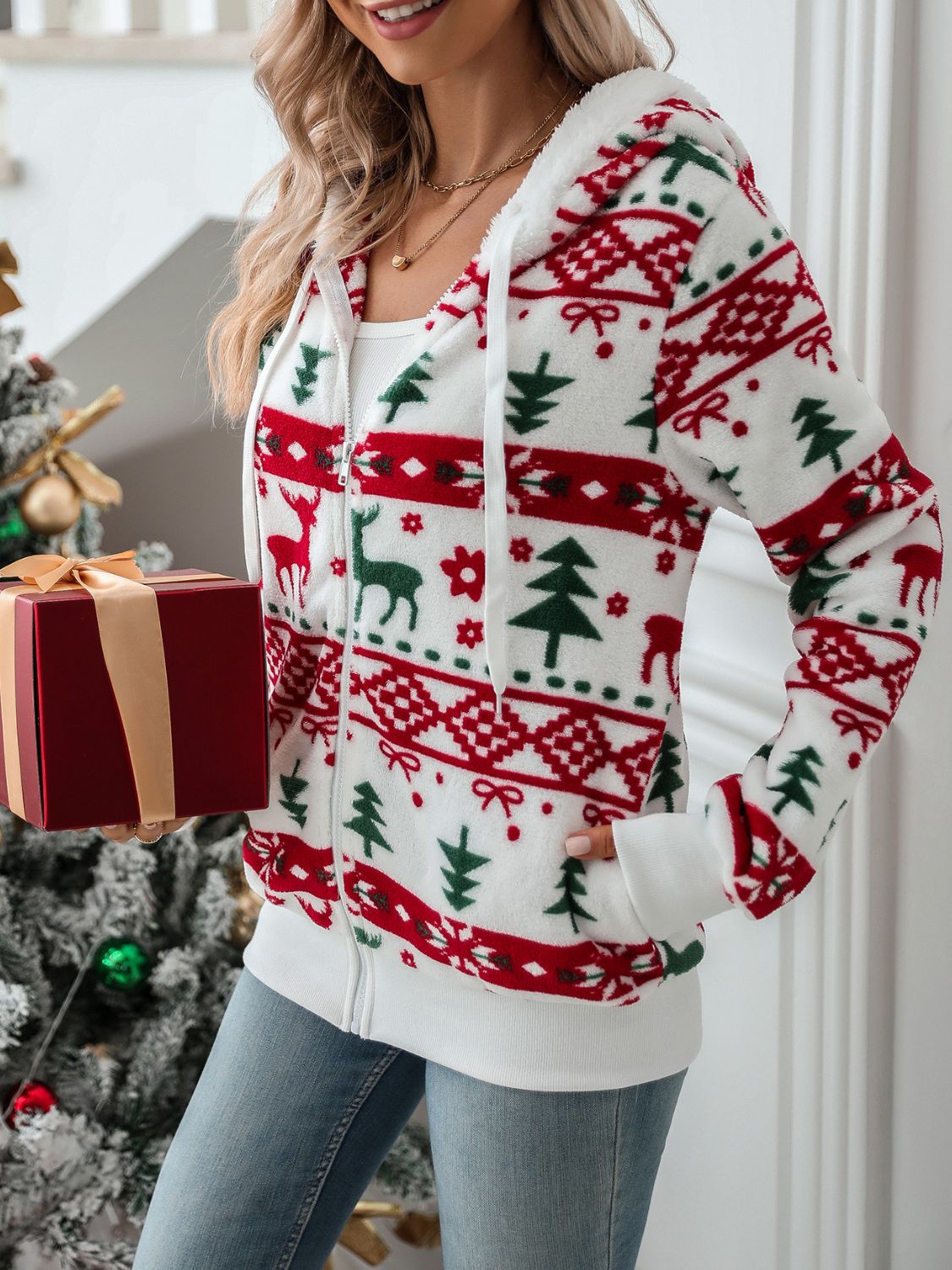 White fleece zip-up hoodie with festive red and green Fair Isle pattern, featuring reindeer and trees.