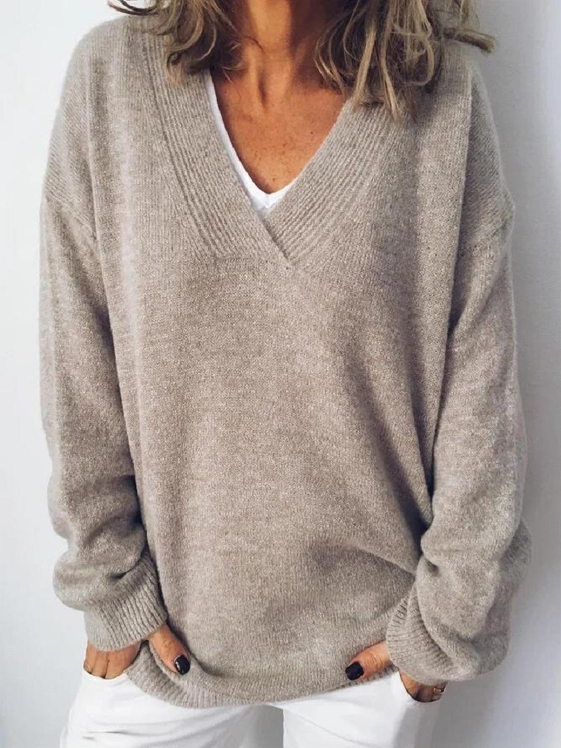 Relaxed V-neck ribbed knit sweater in tan acrylic, styled casually with white pants.