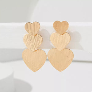 Gold heart-shaped dangle earrings with textured finish
