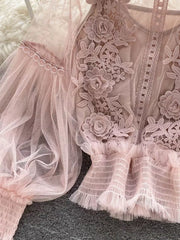 Light pink sheer lace blouse with floral embroidery and ruffled hem.