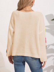 Tan knit sweater with colorful granny square sleeves and a relaxed fit.