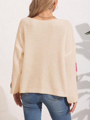 Tan knit sweater with colorful granny square sleeves and a relaxed fit.