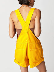 Gold denim short overalls with crisscross straps and cuffed hems.