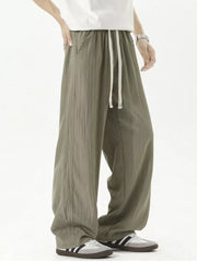 Men's green track pants with drawstring waist and textured fabric.