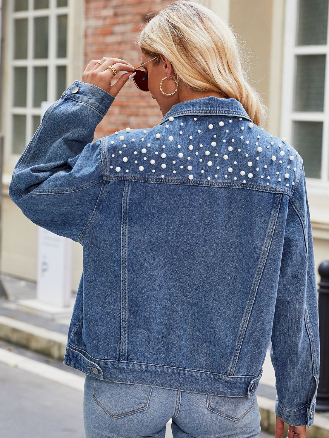 Denim jacket with pearl embellishments on the back yoke, buttoned front, medium wash.