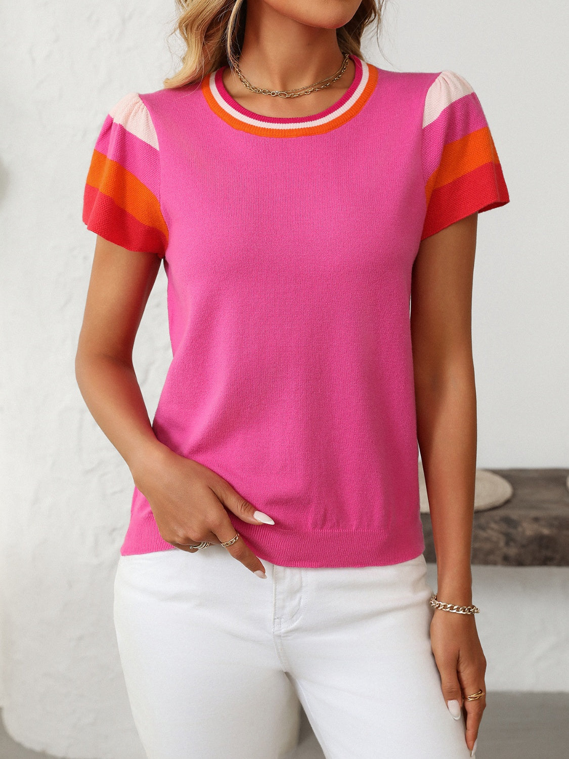 Colorblock knit top with flutter sleeves in hot pink, featuring striped neckline and sleeves.