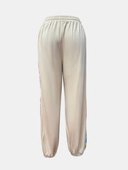 Tan jogger pants with embroidered stripe detail on the side seam.