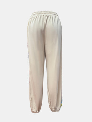 Tan jogger pants with embroidered stripe detail on the side seam.