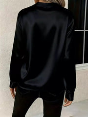 Black satin maternity blouse with buttoned cuffs and a notched V-neck.