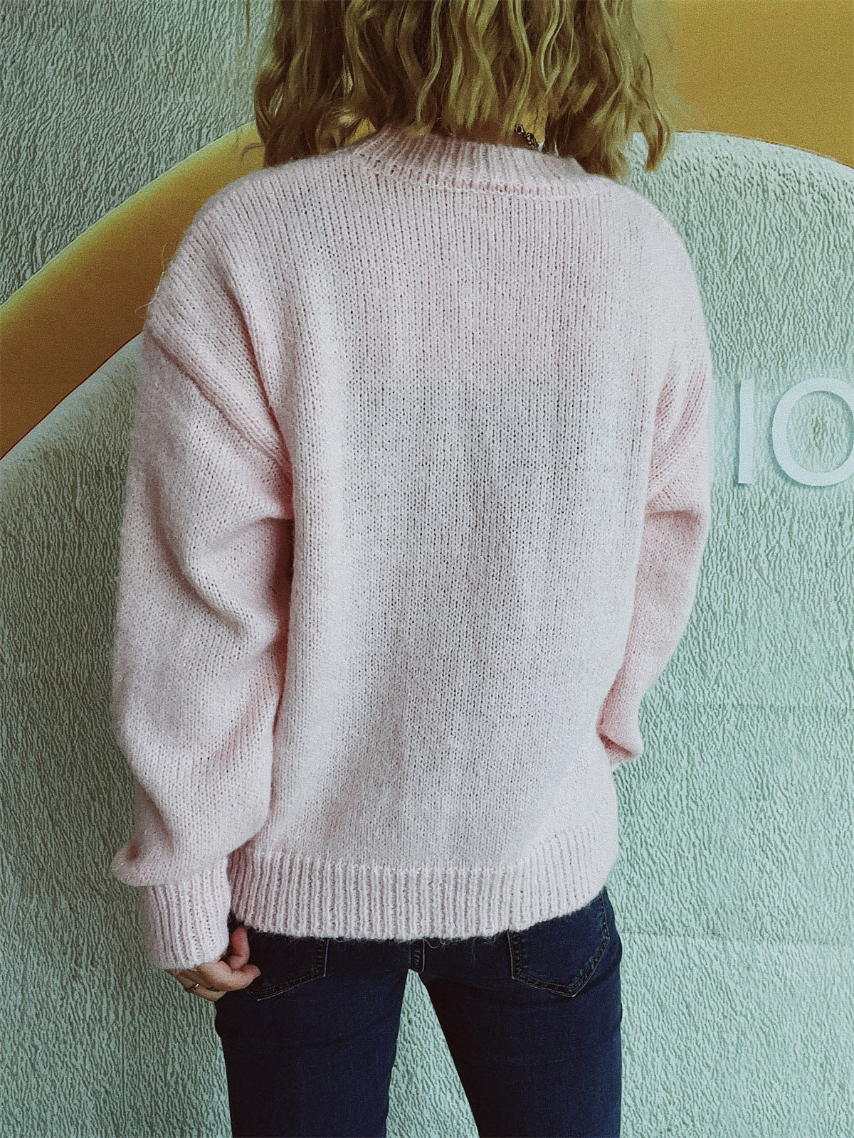 Blush pink knit crewneck sweater with embellished bow detail.