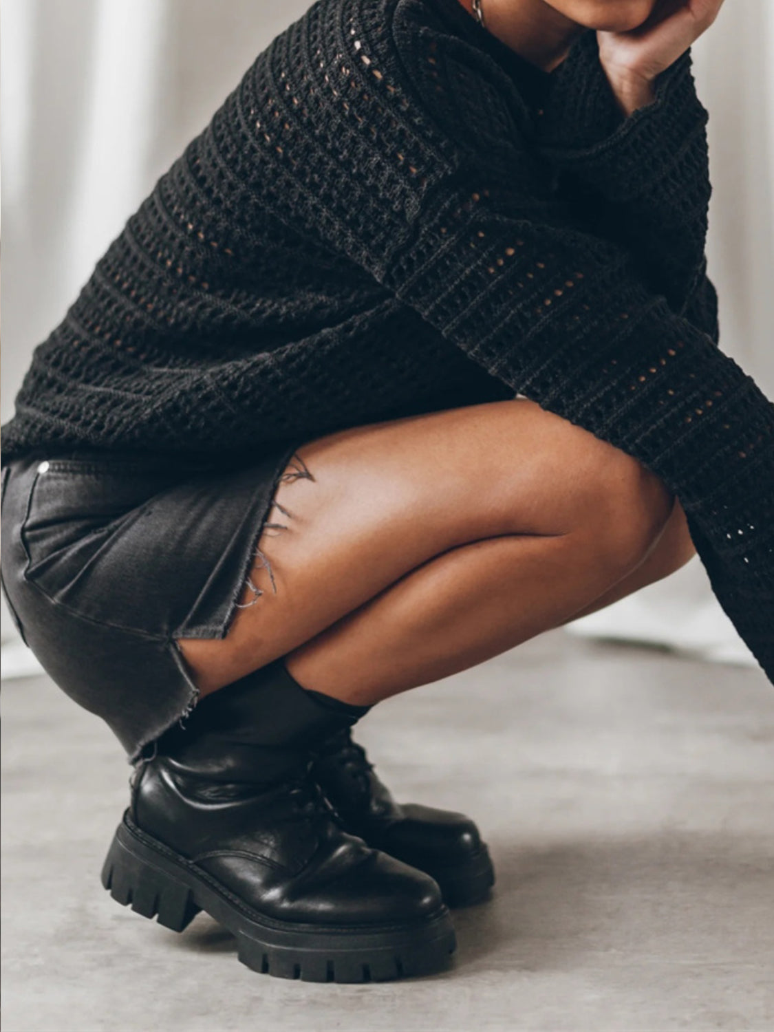 Black open-knit sweater with bell sleeves and a casual cut.