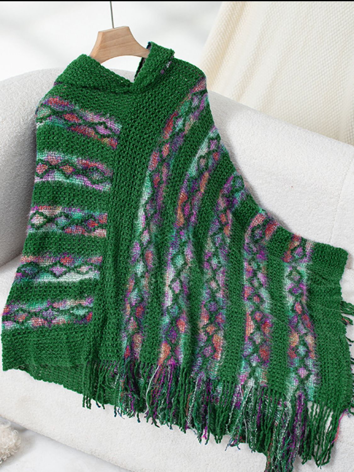 Dark green hooded knit cape with colorful diamond pattern and fringe detail