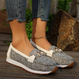 Round toe slip-on loafers with buckle detail in grey textured fabric and white trim.