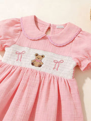 Pink baby dress with smocked bodice, teddy bear embroidery, and puff sleeves.