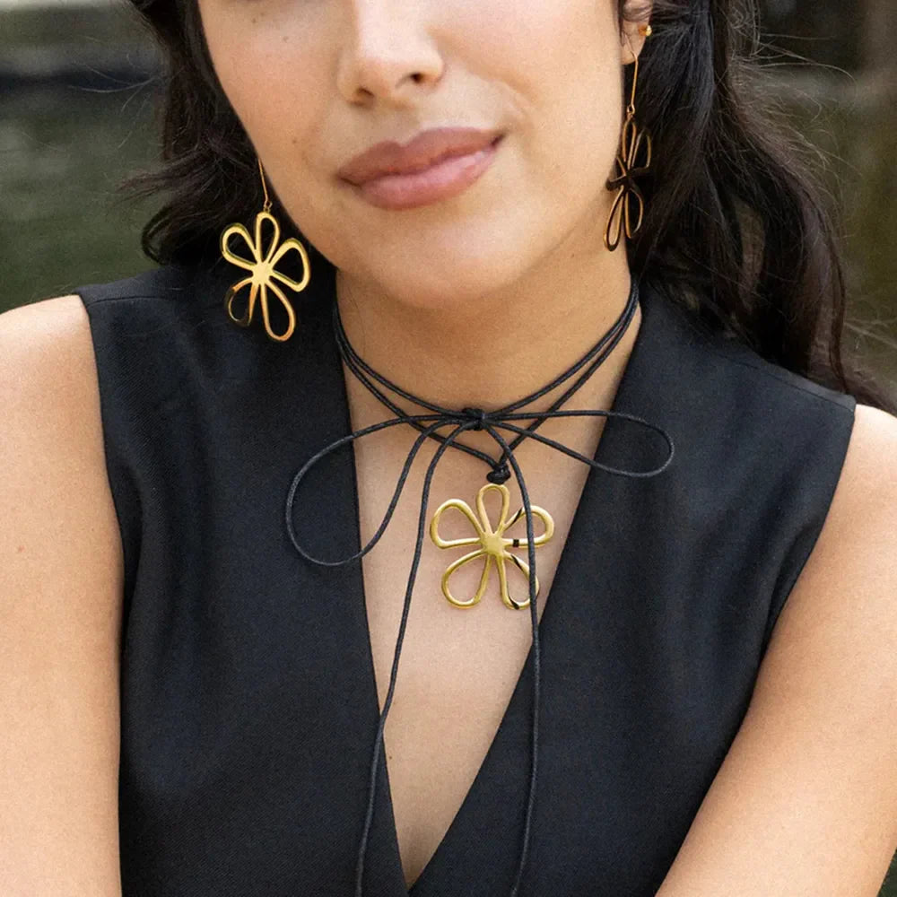 Gold sculpted petal drop earrings and matching pendant necklace on a black cord.