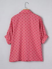 Pink button-down shirt with red hearts pattern, cuffed short sleeves, and classic collar.