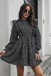 Black dot print dress with ruffle trim, long sleeves, and a cinched waist.
