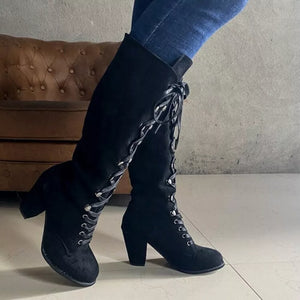 Black suede lace-up block heel boots with decorative lacing details.