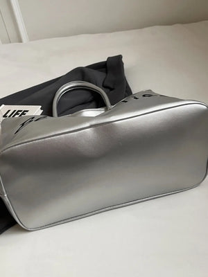 Silver metallic tote bag with black "Better Life" graphic and top handles.