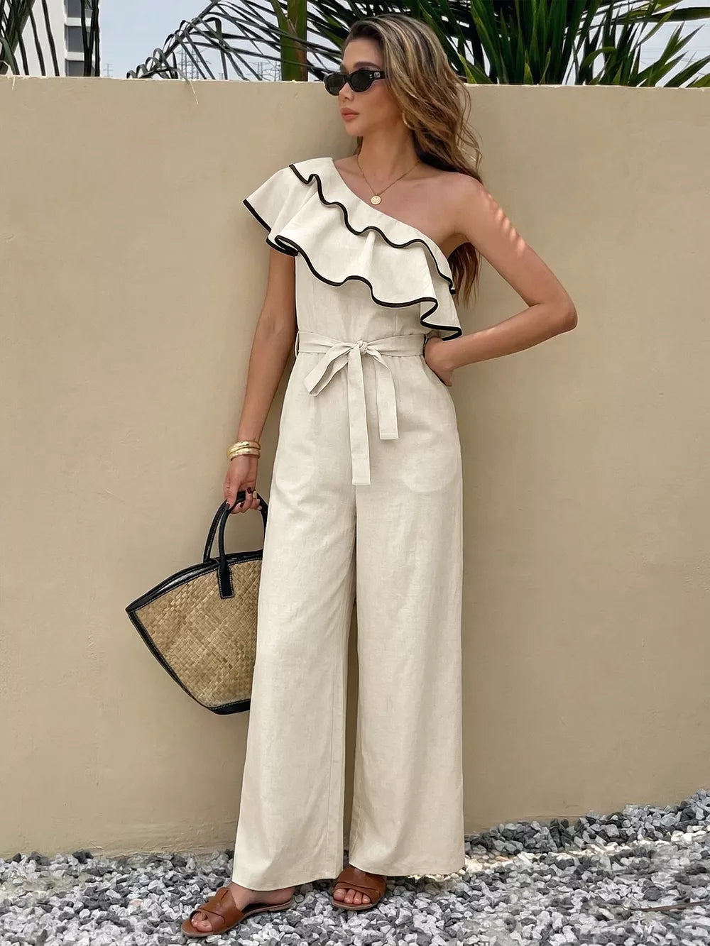 Elegant cream one-shoulder romper with ruffled trim and belted waist.
