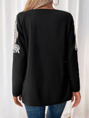 Black ribbed knit zip-front top with white lace trim on sleeves.