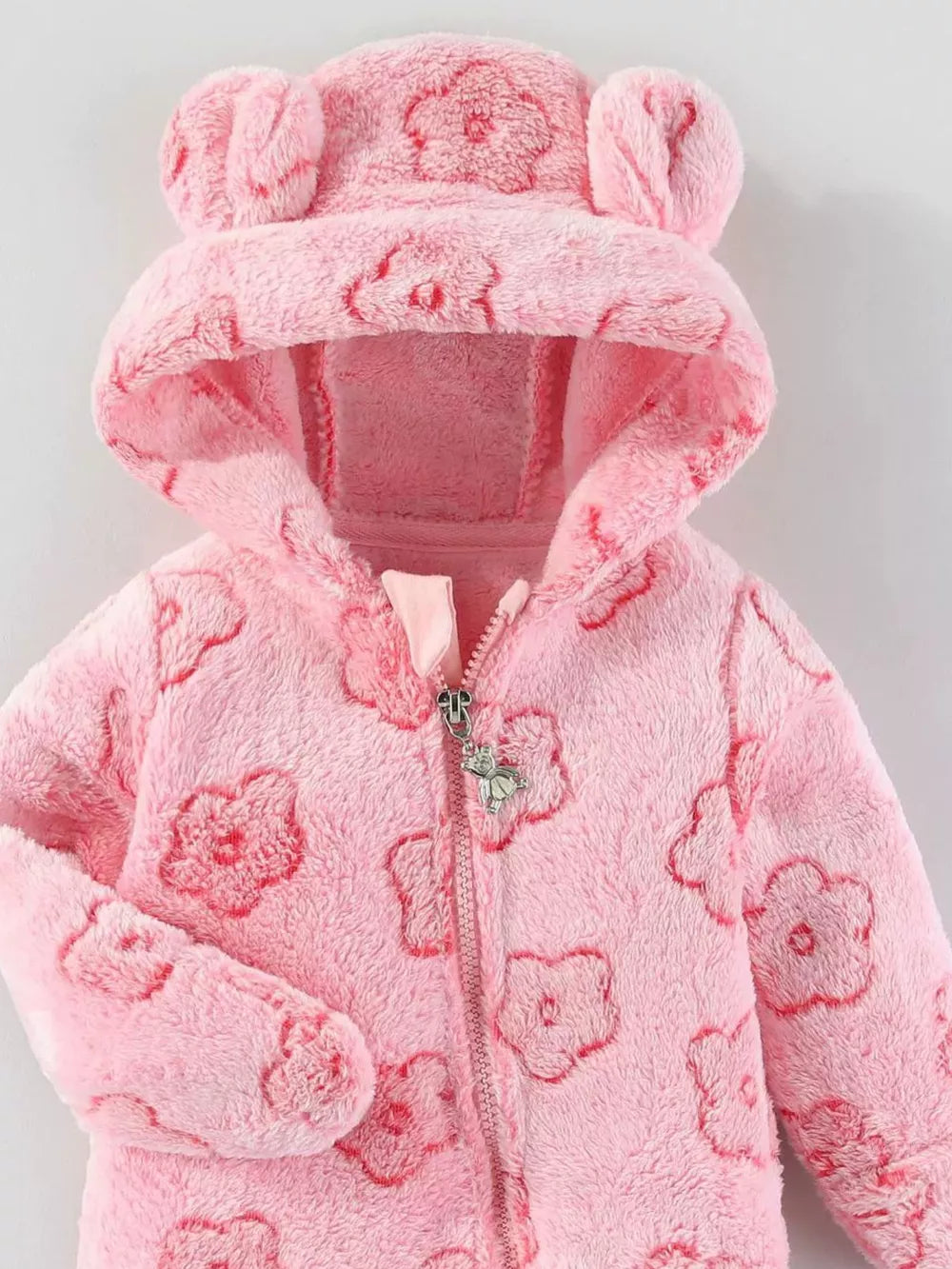 Pink plush one-piece with bear ears hood and flower pattern.