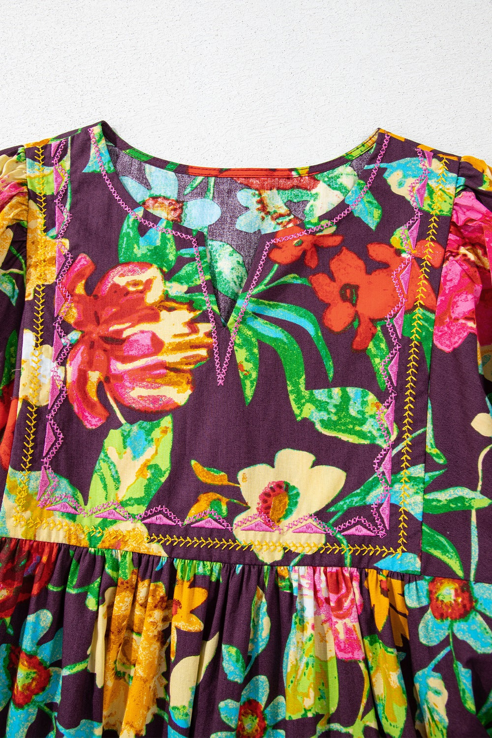 Embroidered floral babydoll blouse with V-neck and gathered waist.