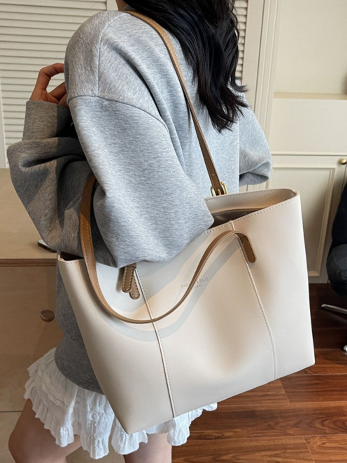 White structured tote bag with brown trim and shoulder strap, made of pu leather.