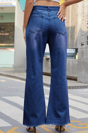 Distressed knee flare denim jeans in dark wash with frayed hem.