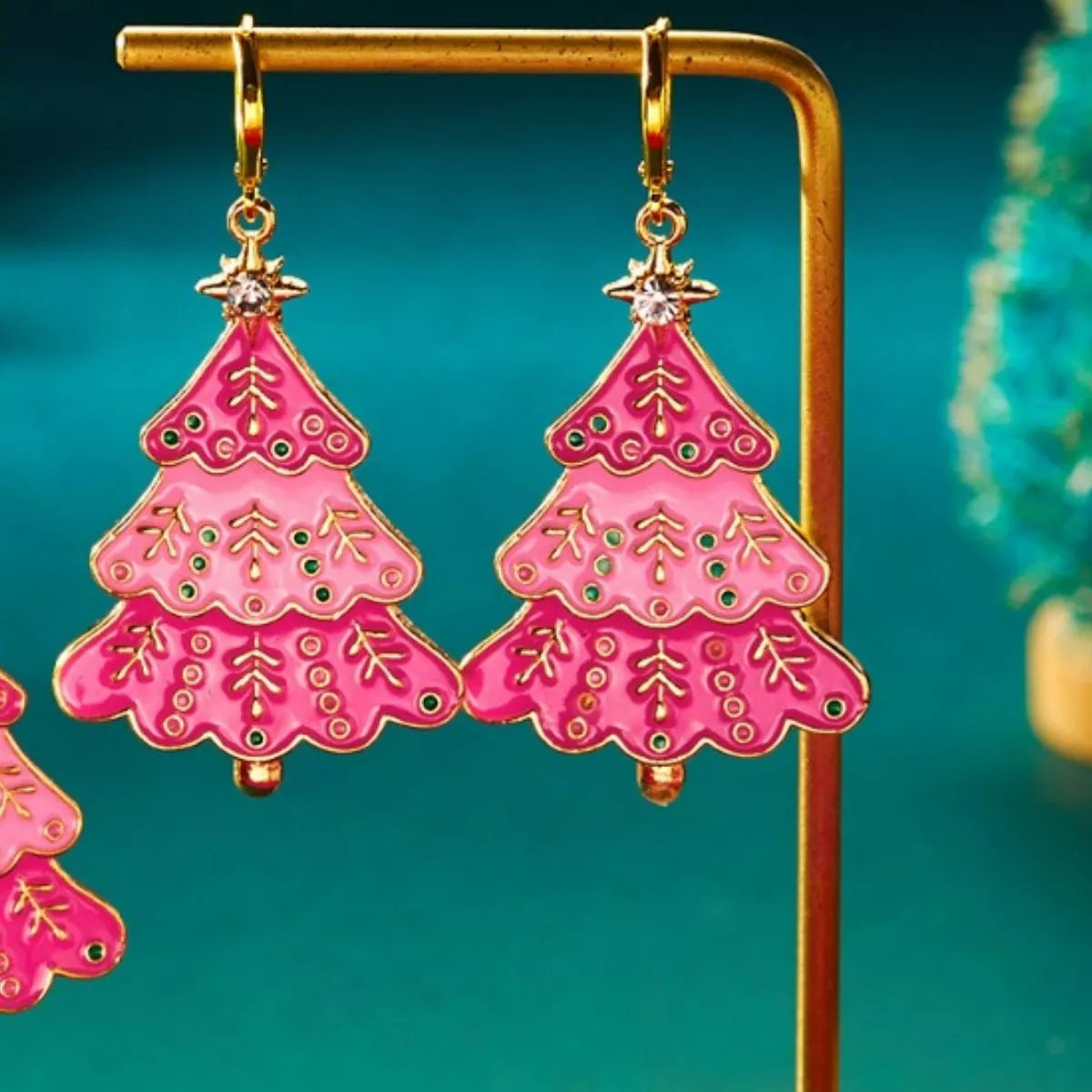 Christmas tree dangle earrings in blush pink with gold accents and green gem details.