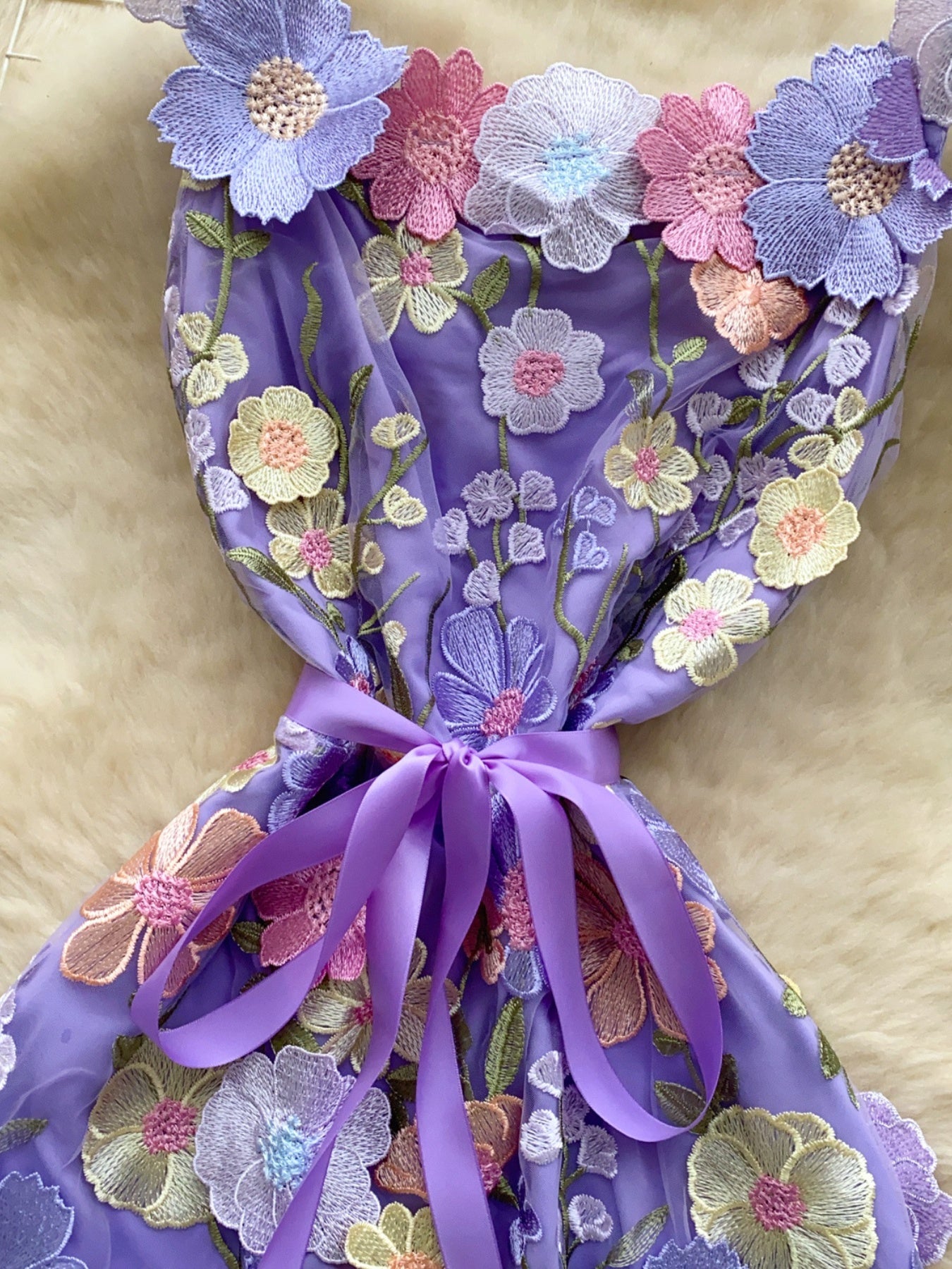 Purple embroidered floral mini dress with a bow detail and colorful flower appliques.