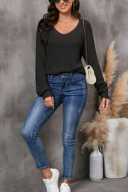 Black knit v-neck pullover sweater with textured detail and balloon sleeves.