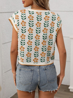 Floral knit sleeveless top in white with orange flowers and green leaves pattern.
