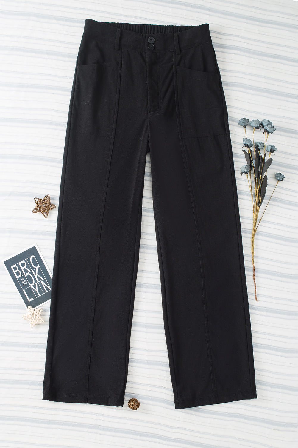 Black seamed front wide leg trousers with buttoned waist and pocket details.