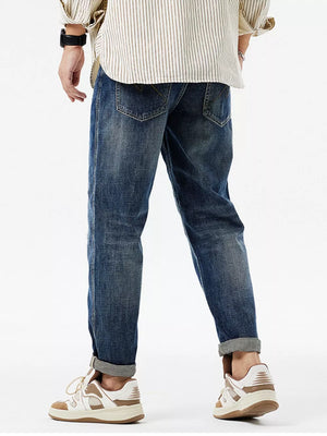 Men's dark blue distressed cotton jeans with cuffed hems and patchwork details.