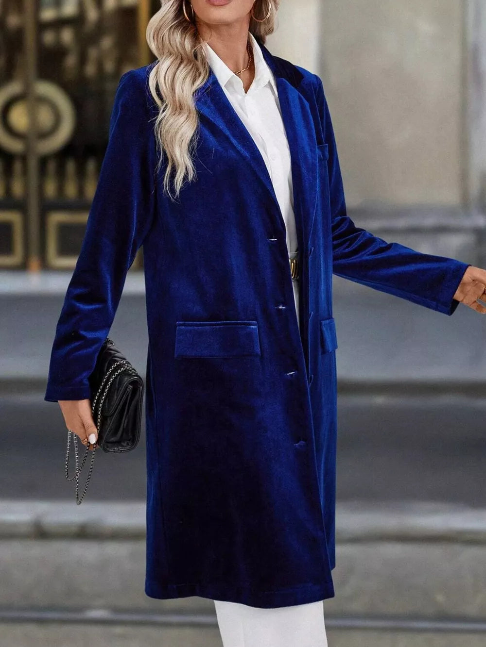 Longline velvet trench coat in dark blue with lapel collar and buttoned front.