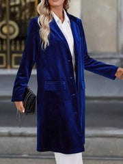 Longline velvet trench coat in dark blue with lapel collar and buttoned front.