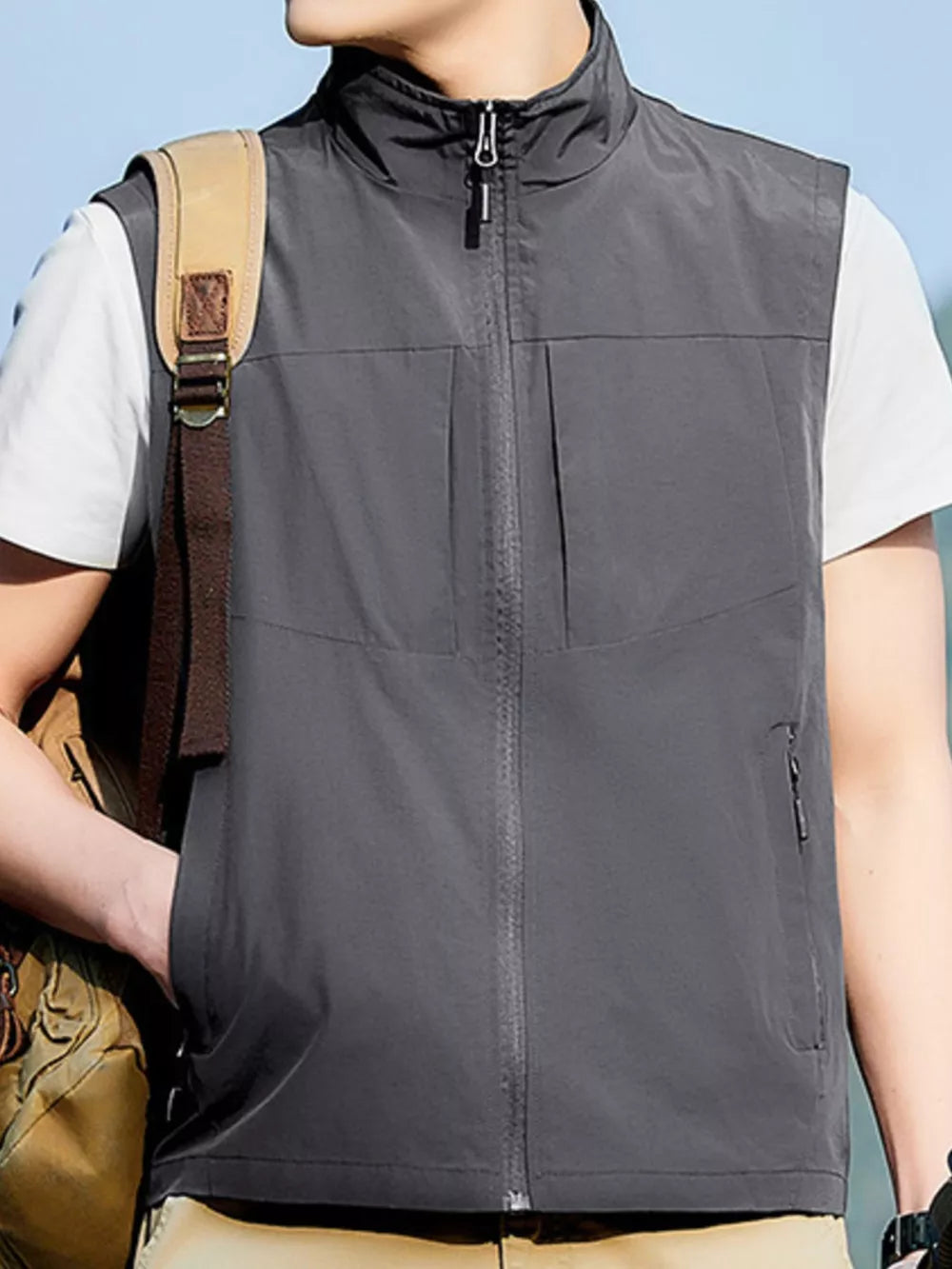 Grey zip up vest with stand collar and zippered pockets, worn by a man.