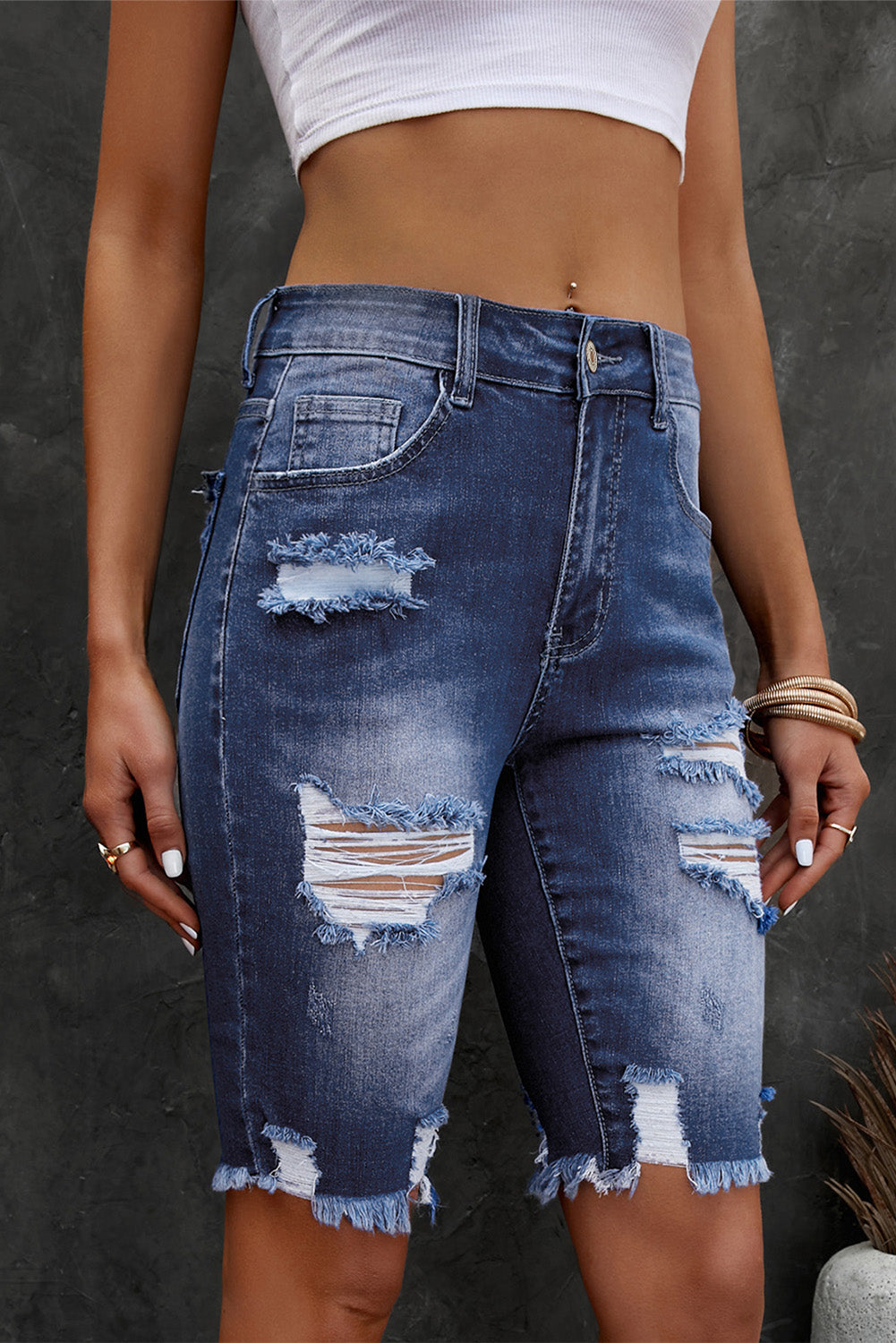 Ripped knee denim bermuda shorts in medium wash with frayed hem and distressed details.