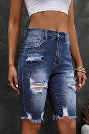 Ripped knee denim bermuda shorts in medium wash with frayed hem and distressed details.