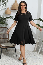Black midi dress with short sleeves, laser cutouts at neckline and hem, and a flared skirt.