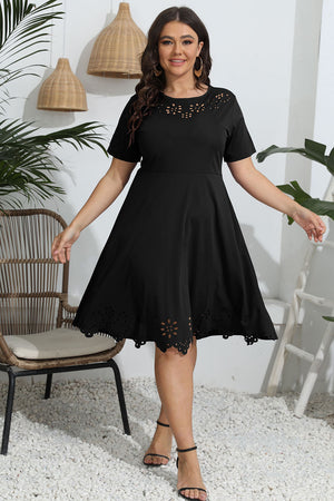 Black midi dress with short sleeves, laser cutouts at neckline and hem, and a flared skirt.