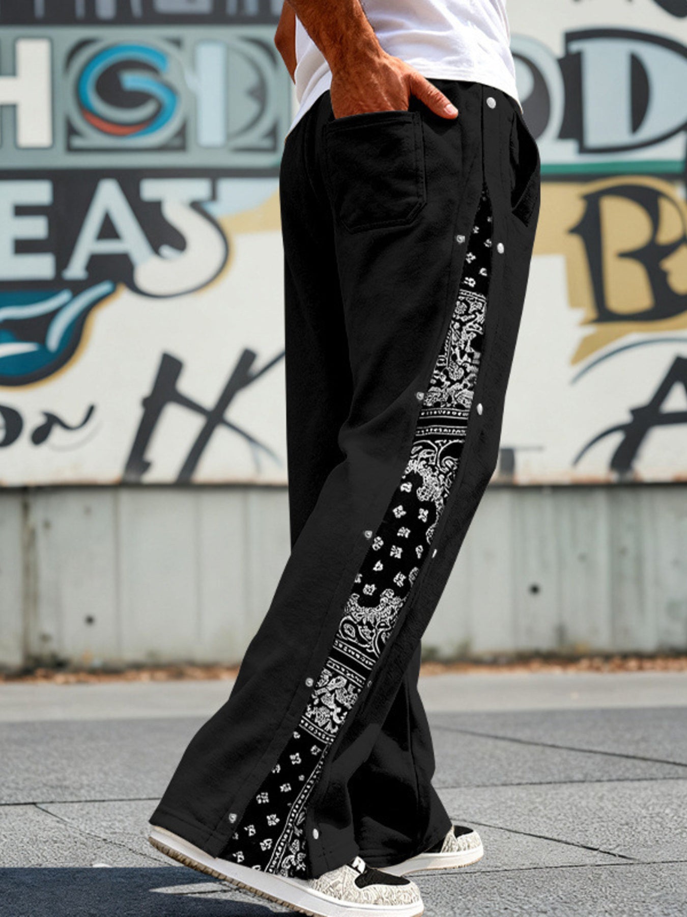Black sweatpants with wide legs and side snaps, featuring a bandana print stripe.