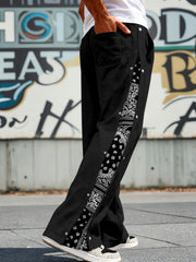 Black sweatpants with wide legs and side snaps, featuring a bandana print stripe.