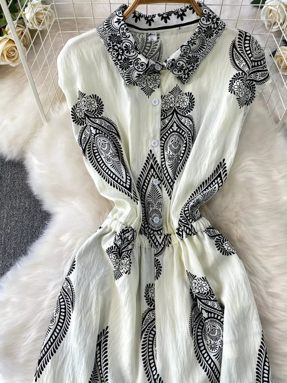 White button-down romper with black paisley print, collared, short sleeves, elastic waist