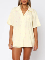 Pastel yellow striped pajama set with pink floral print, collared button-up top and shorts.