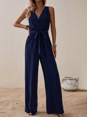 Navy textured wrap-front wide-leg jumpsuit with tie waist and V-neck.