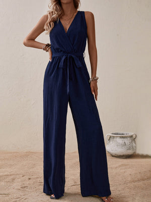 Navy textured wrap-front wide-leg jumpsuit with tie waist and V-neck.